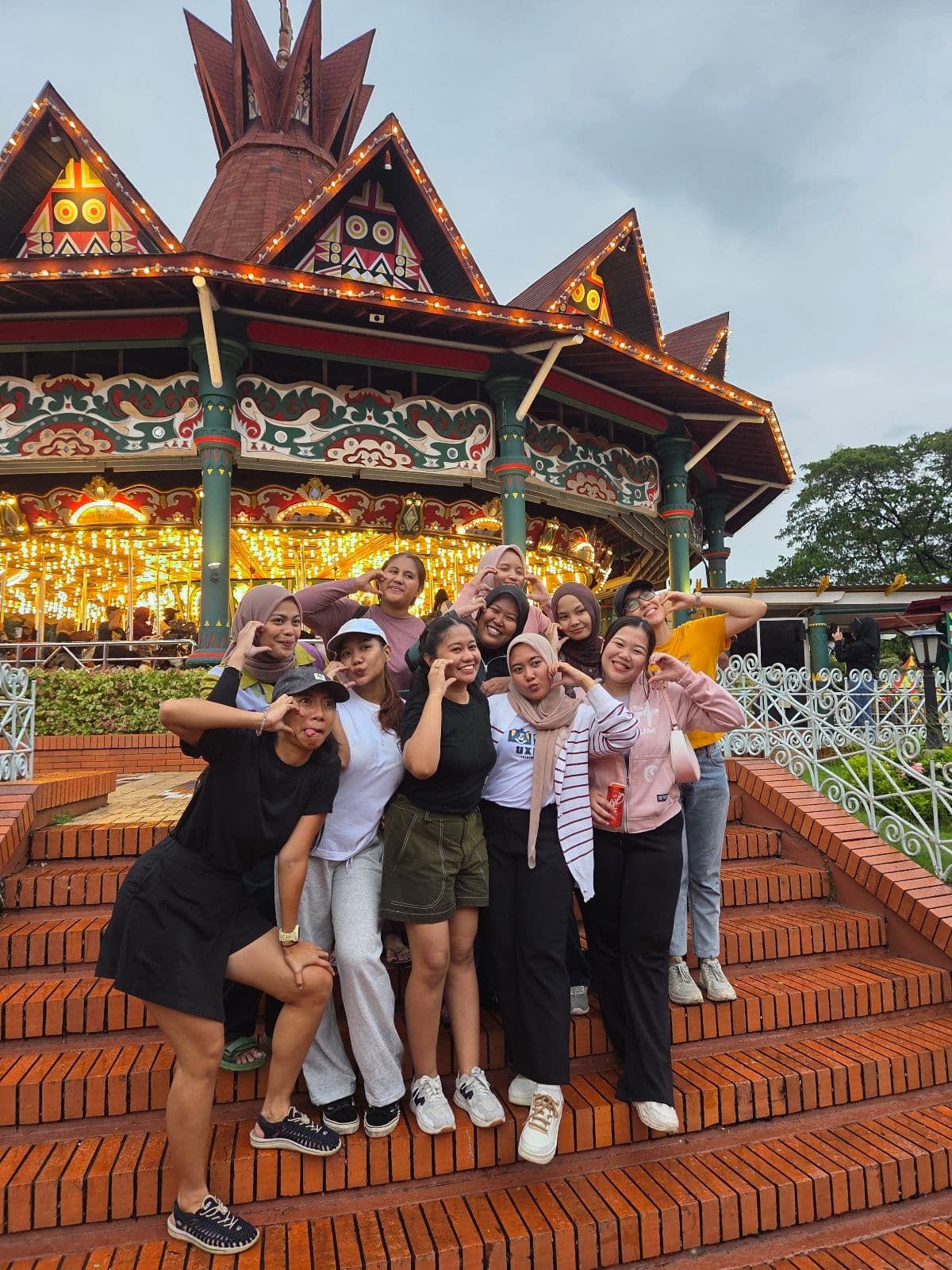 Coworkers making playful poses by a carousel