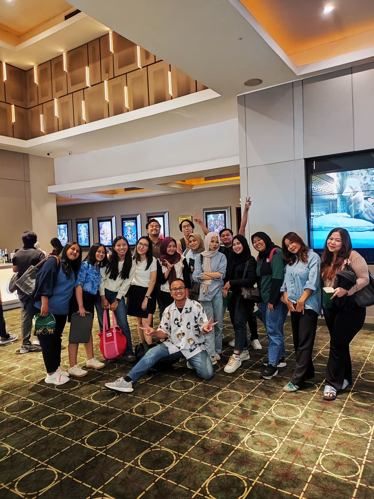 Coworkers posing together in a cinema lobby
