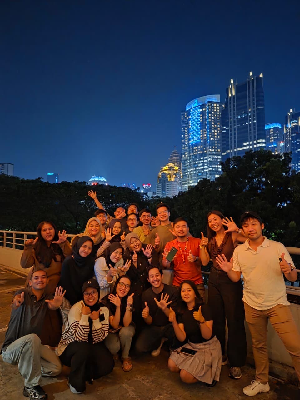 Coworkers posing together beneath a city skyline at night