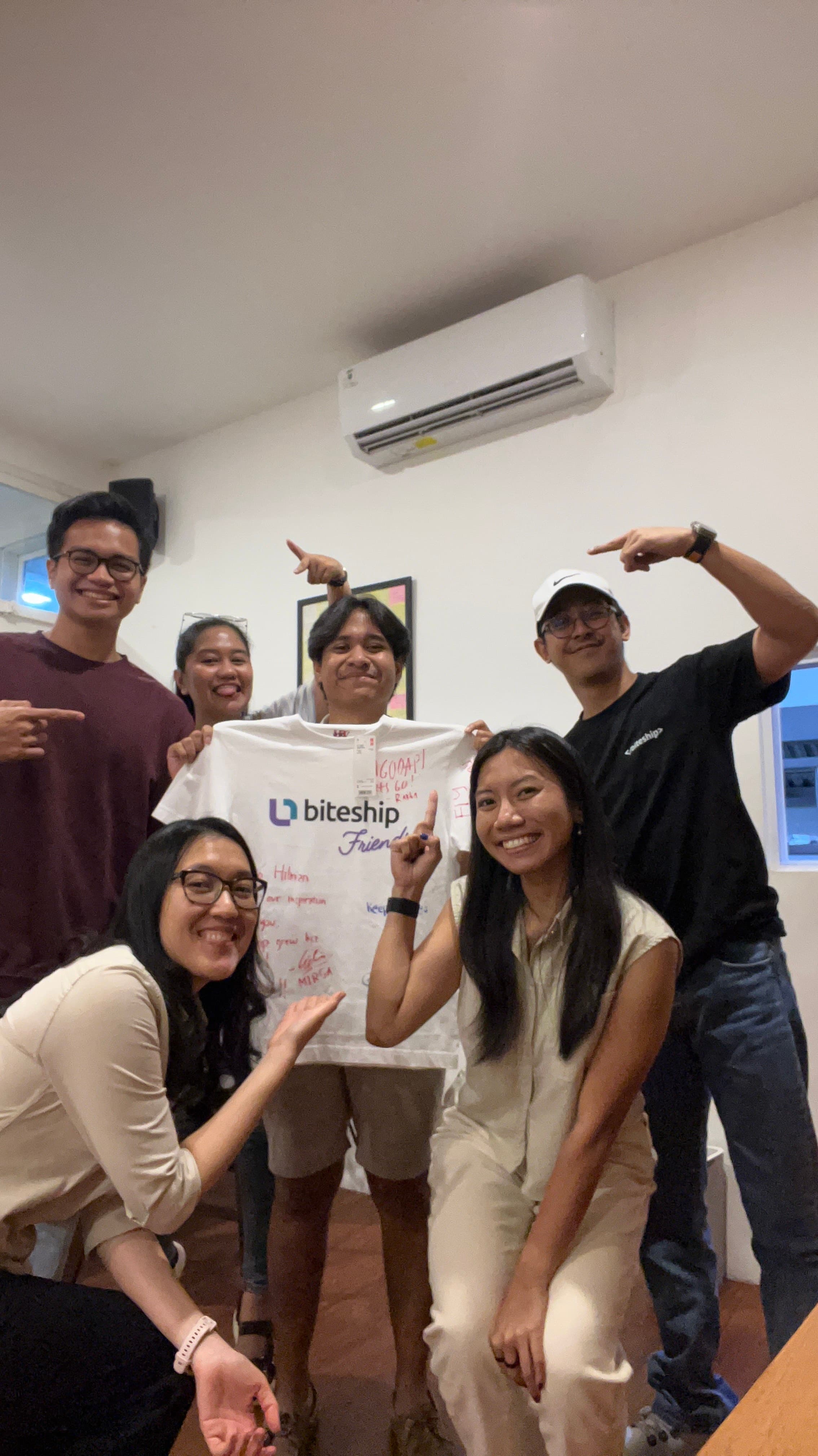 Coworkers gathered around a signed Biteship shirt