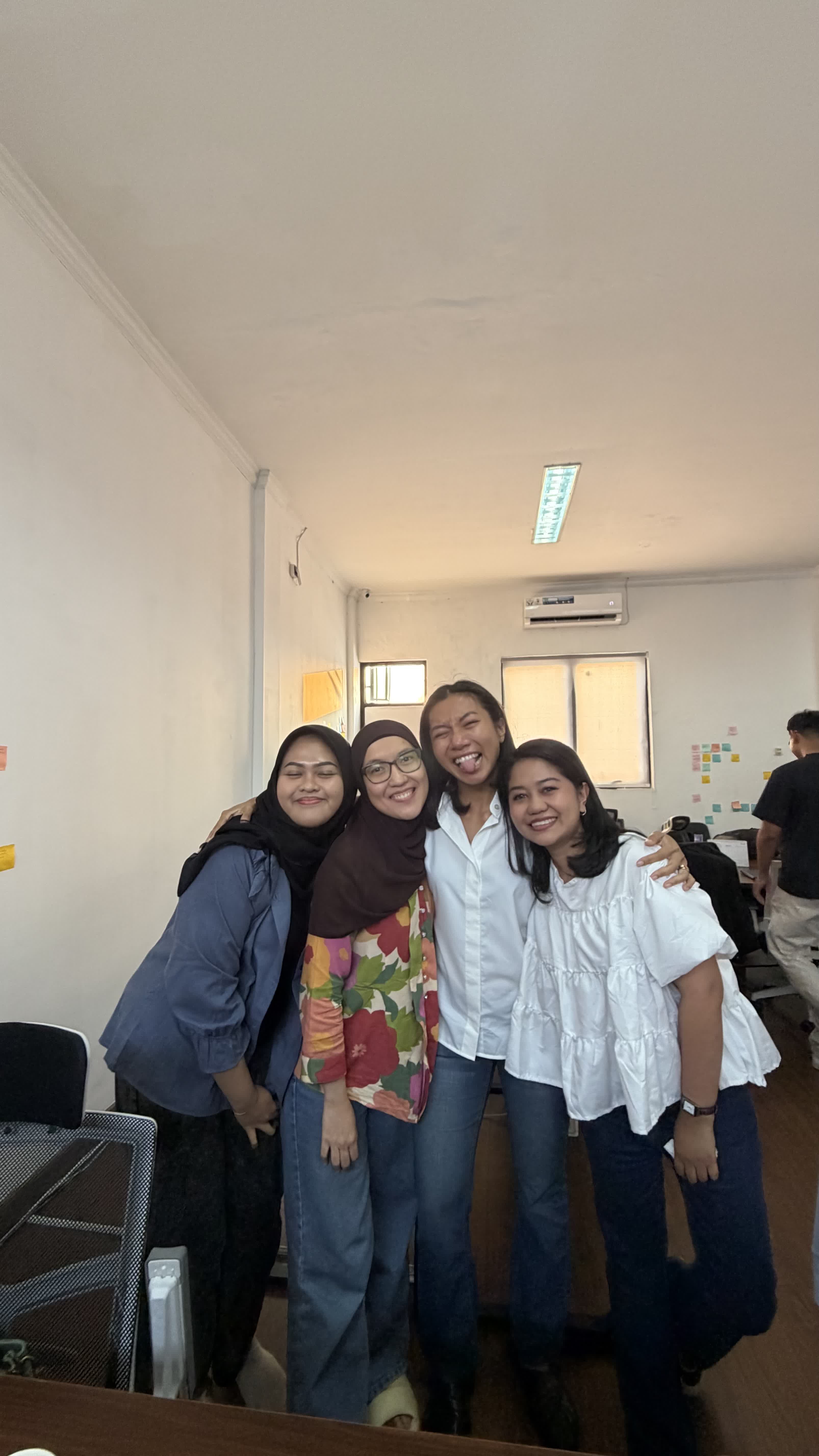 Four coworkers standing arm in arm in the office