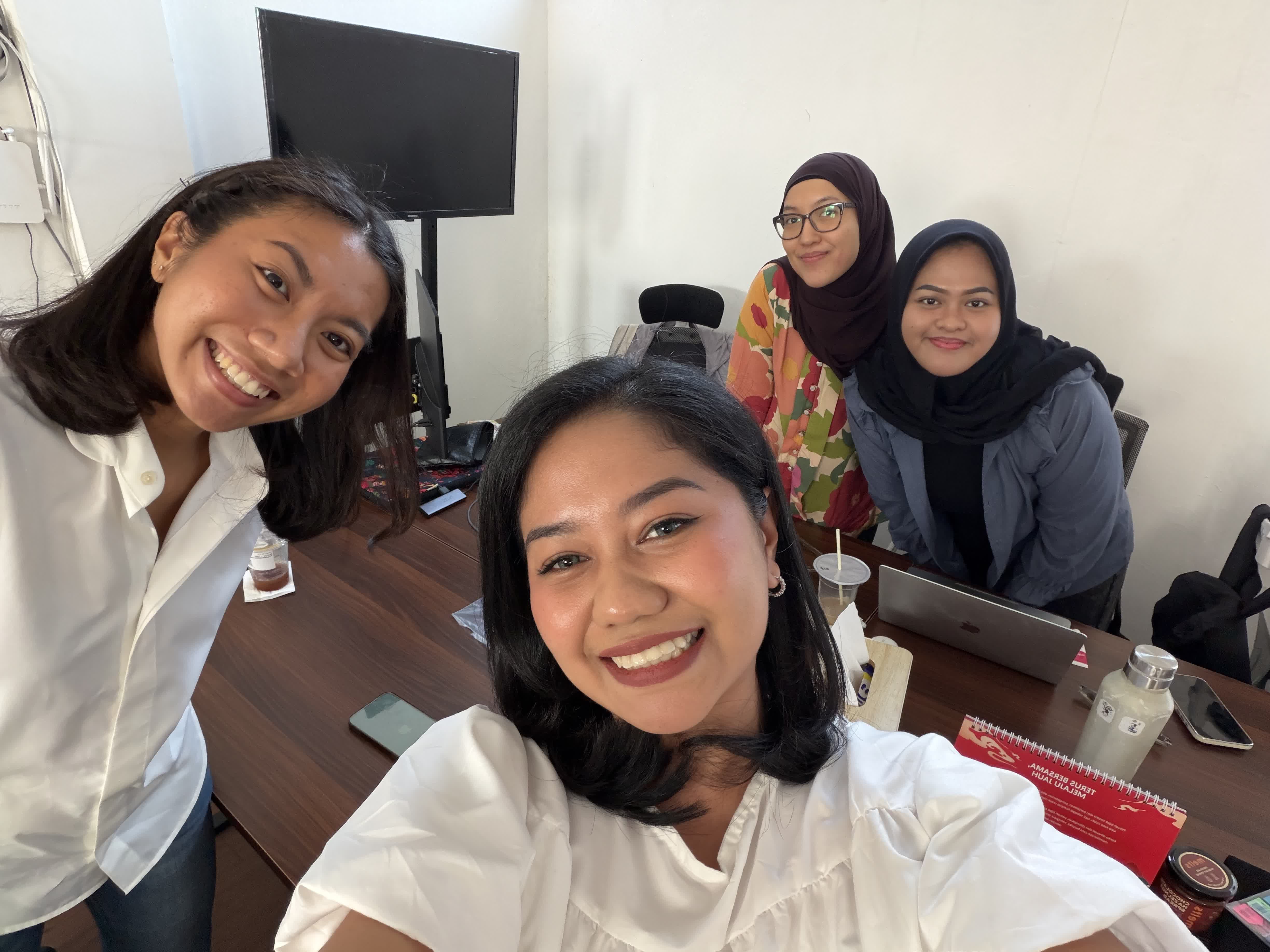 Four coworkers taking a selfie around an office desk