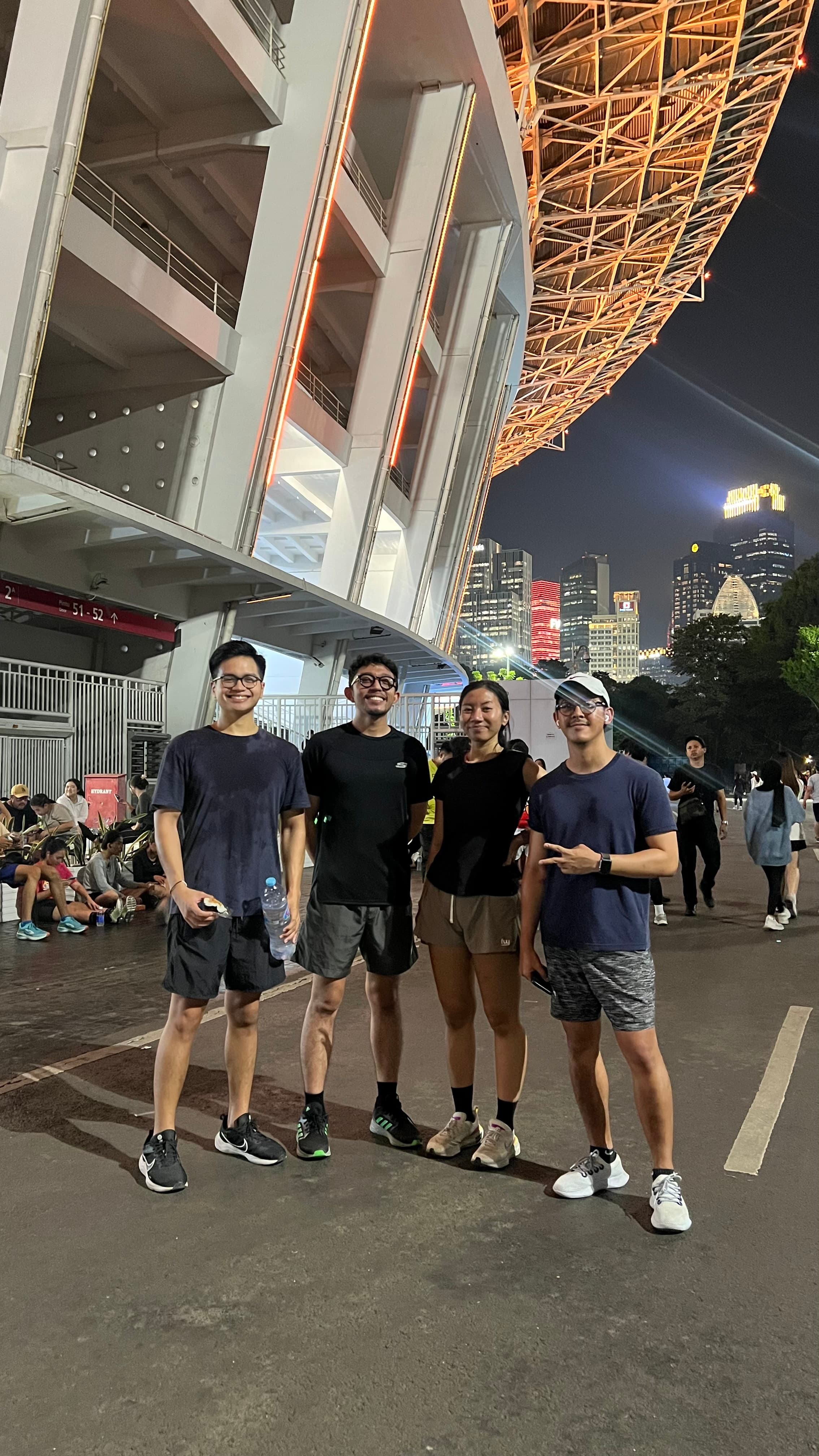 Four friends posing outside a stadium at night