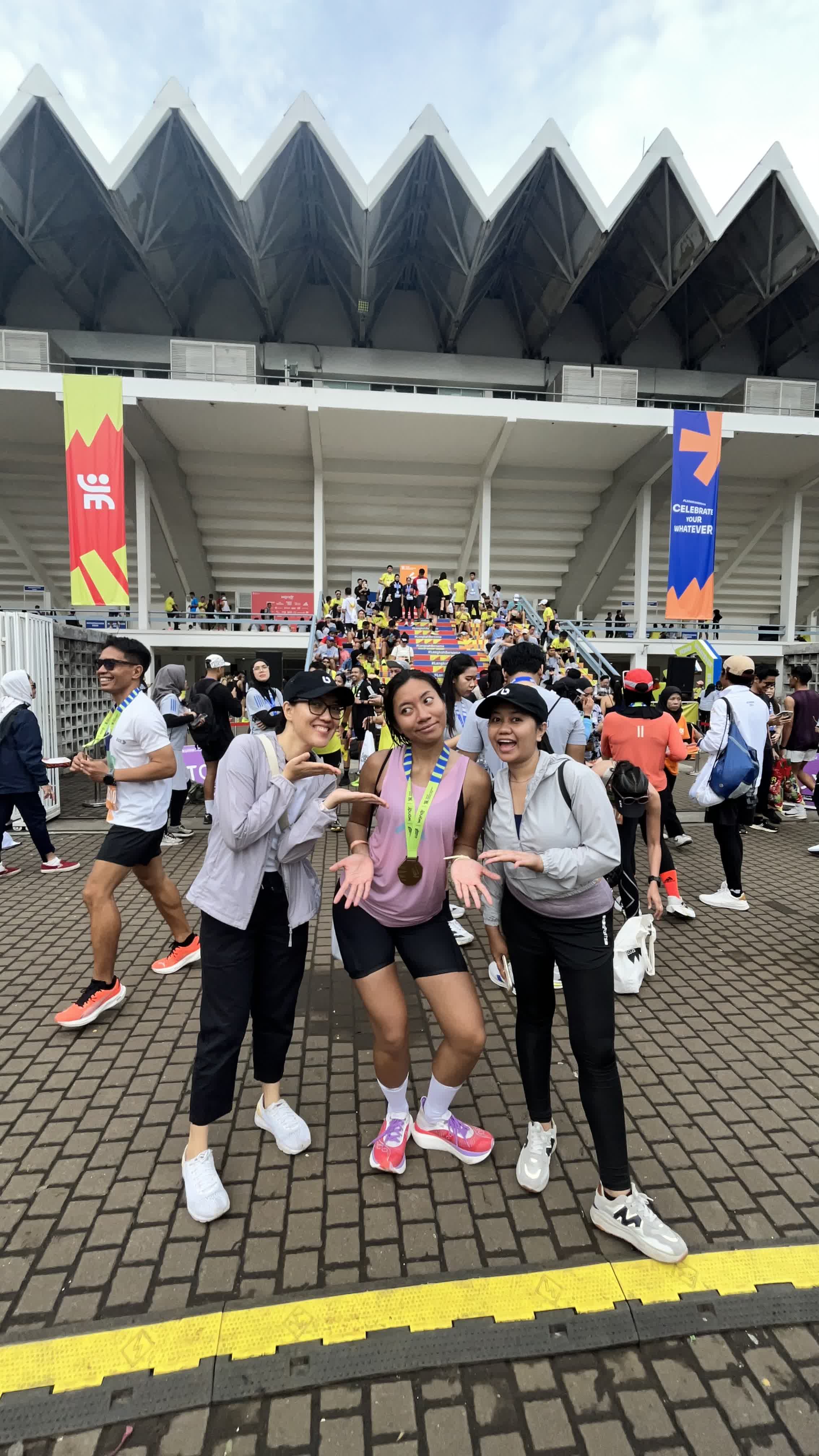 A medal-wearing runner posing with two friends