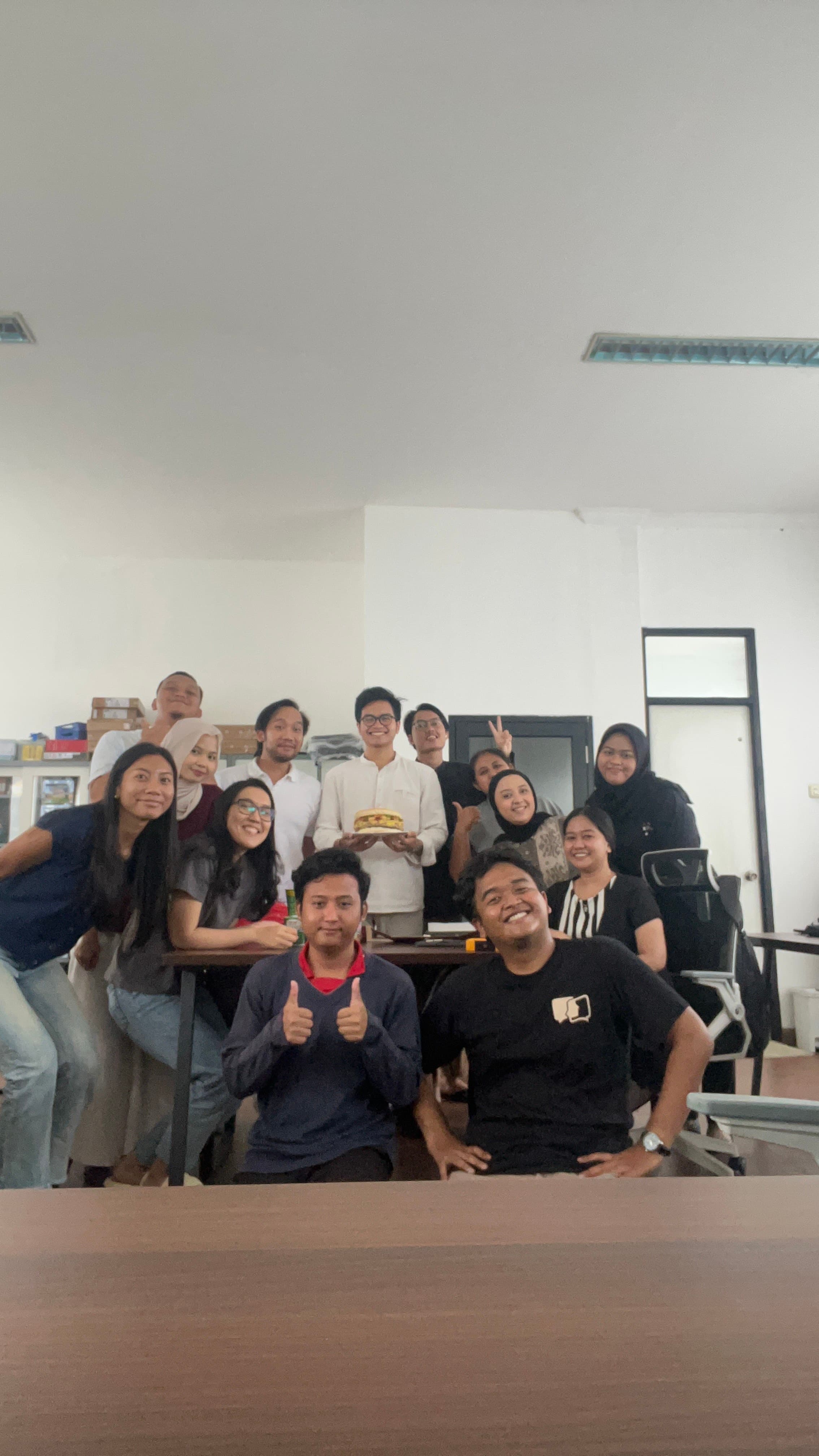 An office celebration gathered around a cake