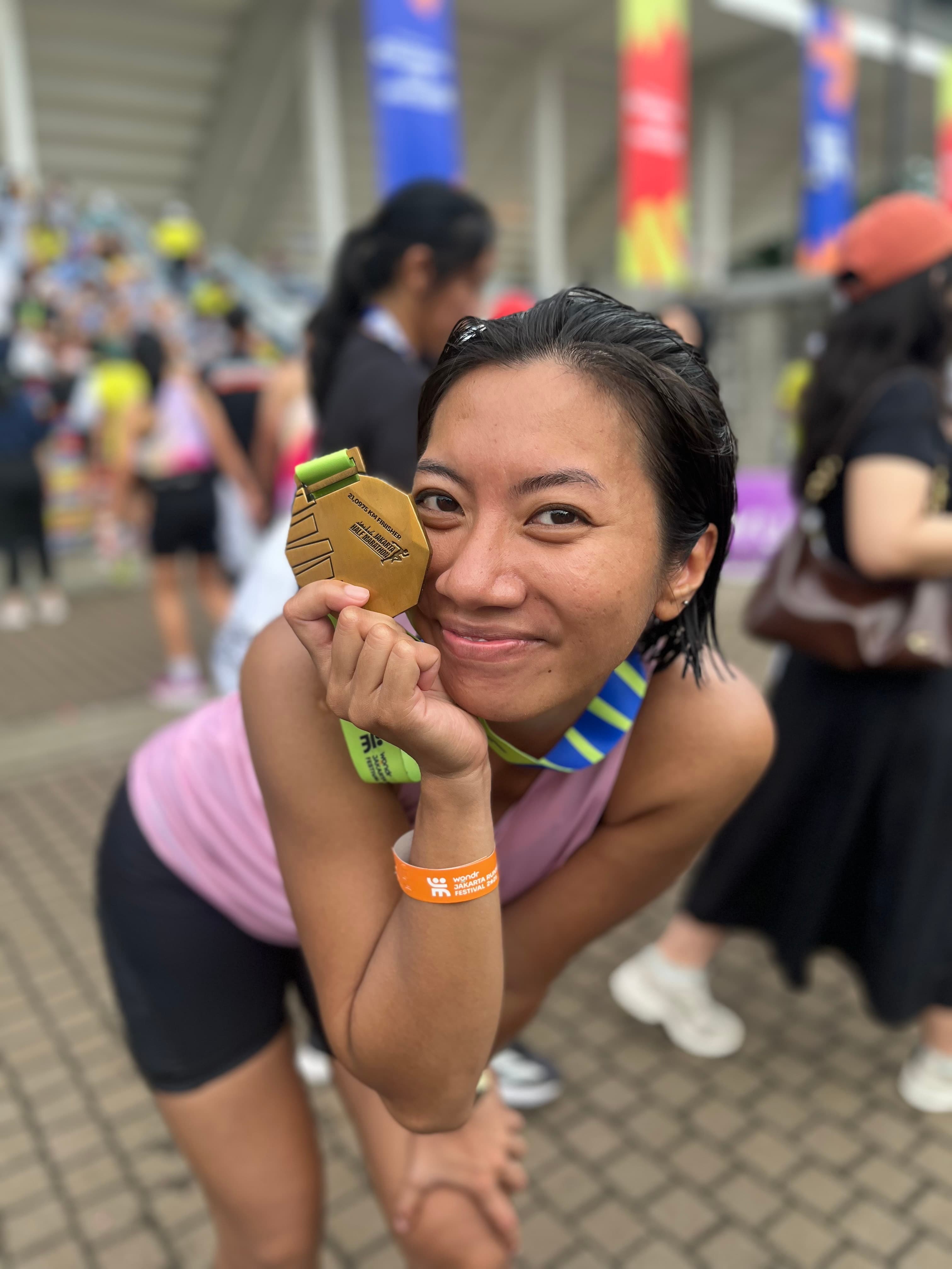 A runner smiling and showing her finisher medal