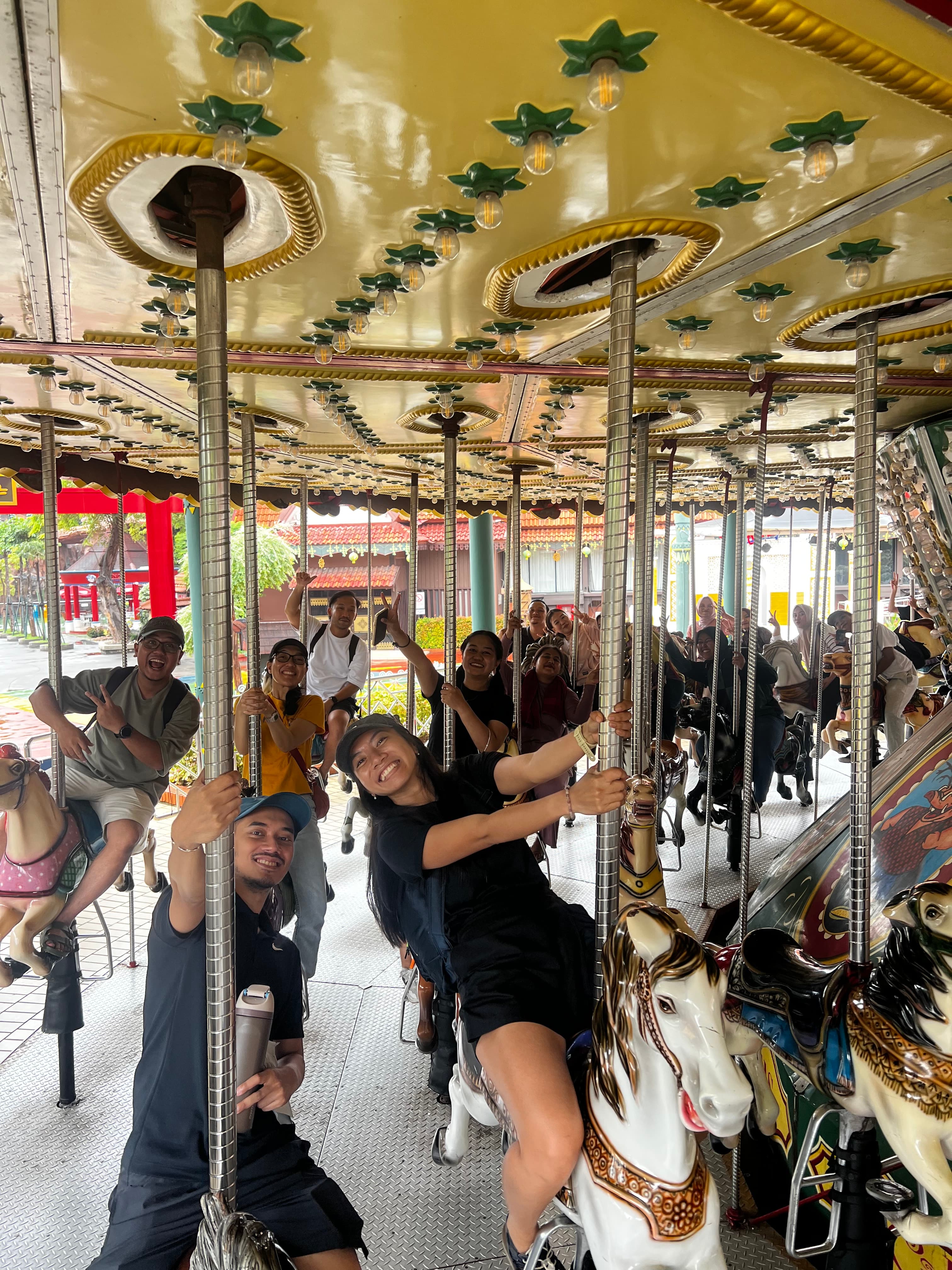 Coworkers smiling together while riding a carousel