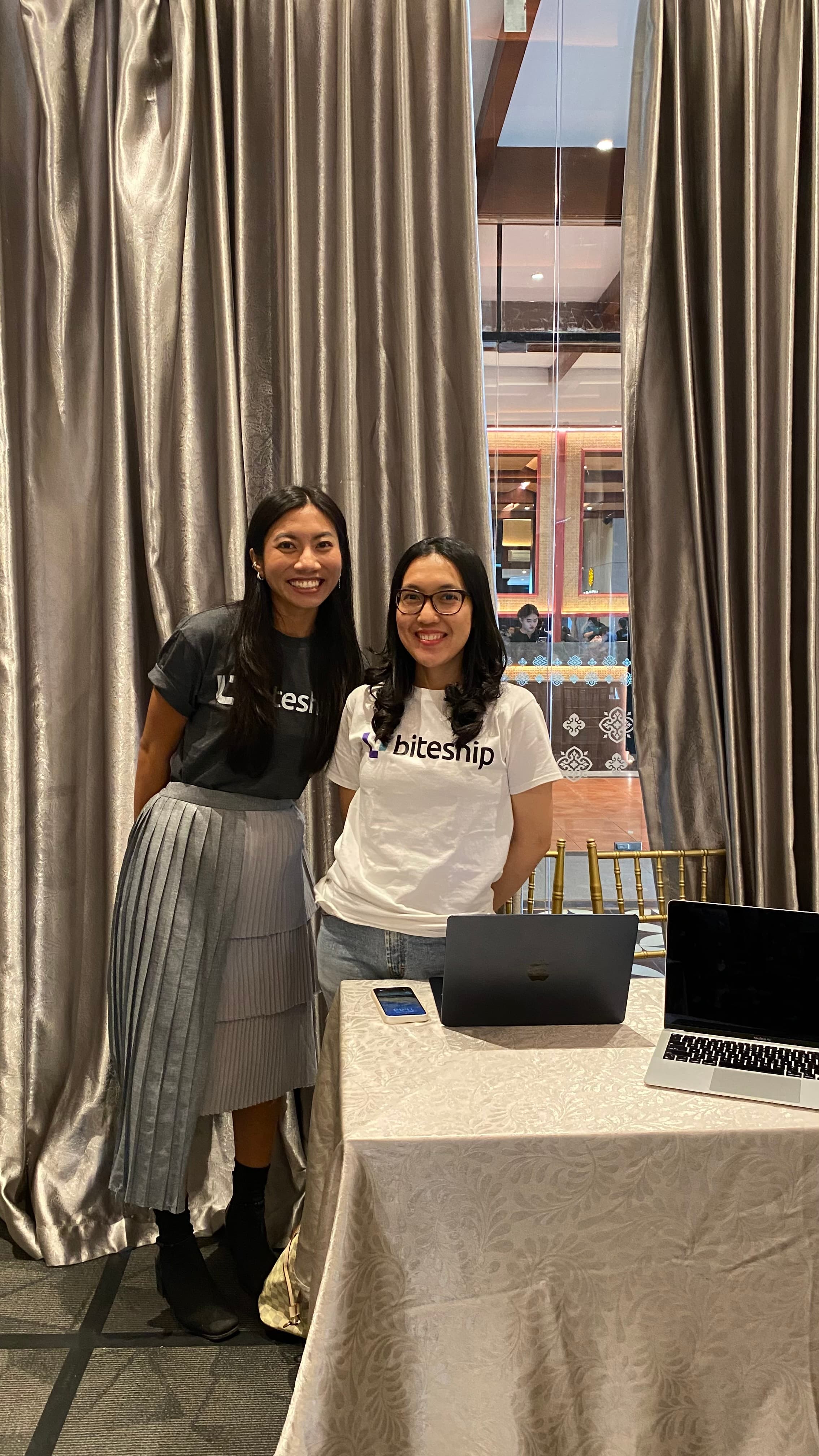 Two coworkers posing together at an event booth